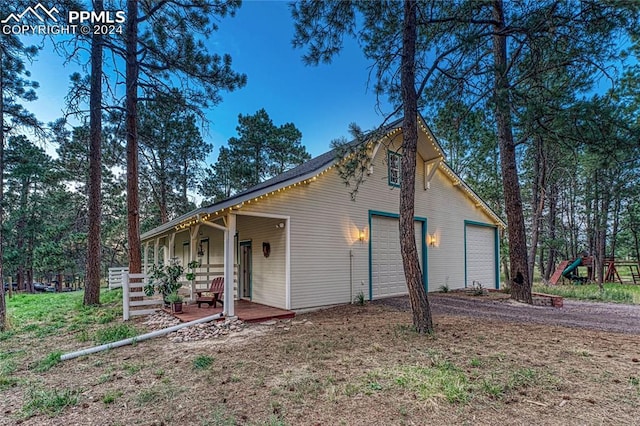 exterior space with a garage, covered porch, and a playground