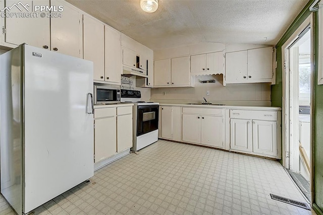 kitchen with electric stove, light floors, stainless steel microwave, freestanding refrigerator, and under cabinet range hood