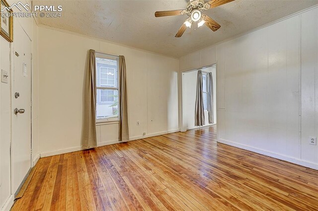 empty room featuring ceiling fan, light hardwood / wood-style flooring, and a textured ceiling