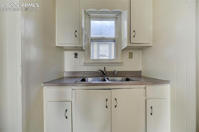 kitchen featuring dark countertops, white cabinetry, and a sink