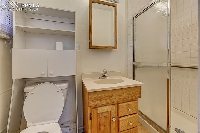 bathroom featuring a shower with shower door, vanity, and toilet