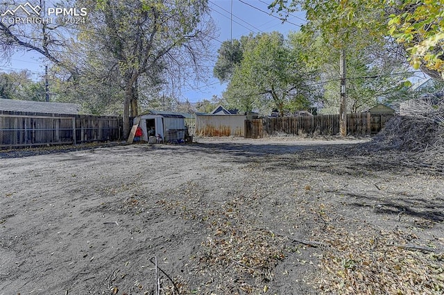 view of yard with a fenced backyard, an outdoor structure, and a storage shed