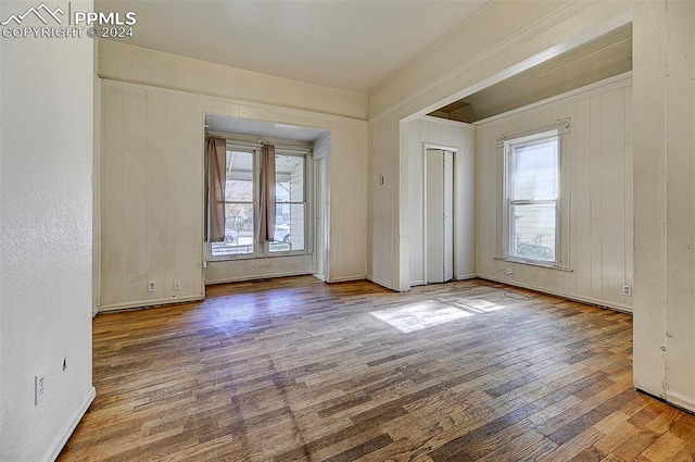 empty room with a healthy amount of sunlight, wood-type flooring, and baseboards