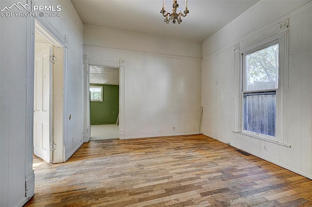 spare room featuring light hardwood / wood-style floors and an inviting chandelier