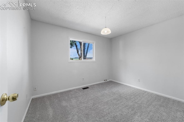 carpeted empty room featuring a textured ceiling