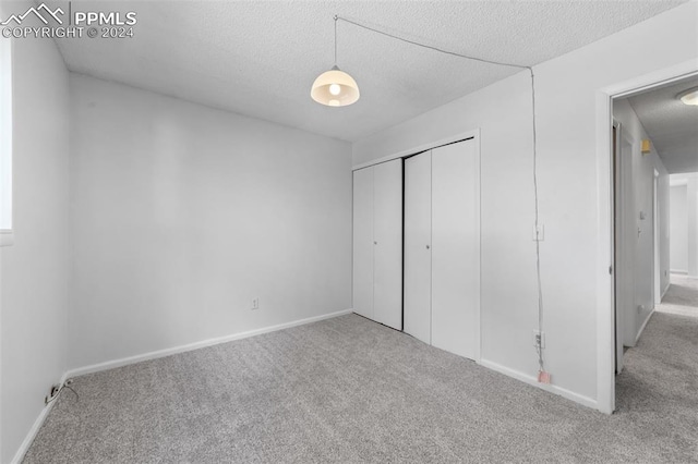 unfurnished bedroom with a textured ceiling, carpet floors, and a closet