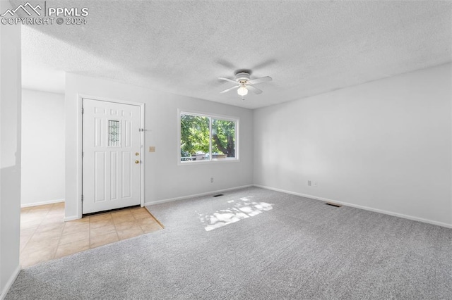 spare room featuring ceiling fan, a textured ceiling, and light carpet