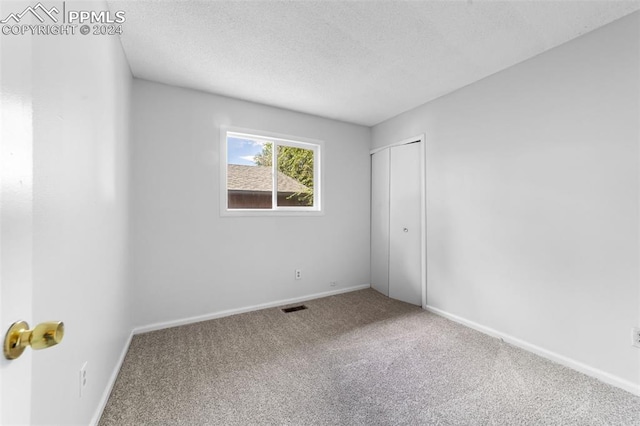 unfurnished bedroom featuring a textured ceiling and carpet