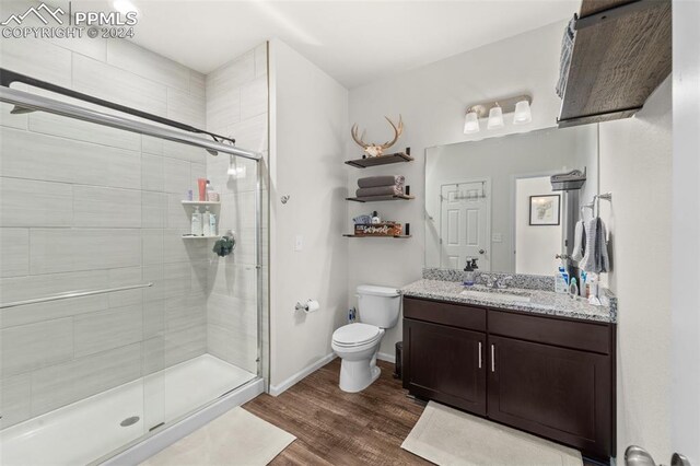 bathroom with hardwood / wood-style floors, toilet, an enclosed shower, and vanity