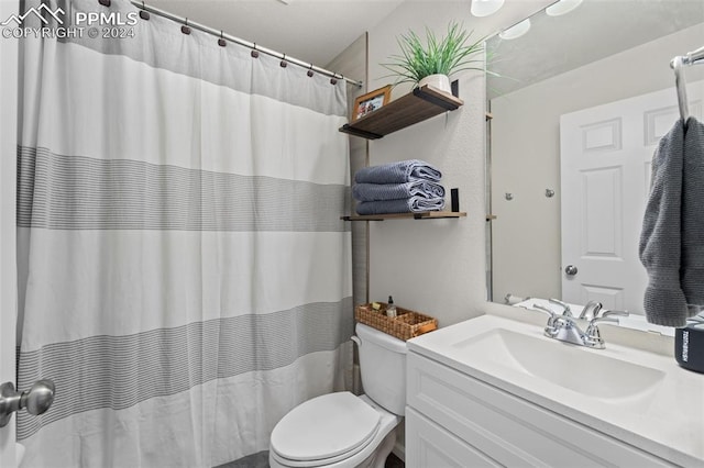 bathroom featuring a shower with shower curtain, toilet, and vanity