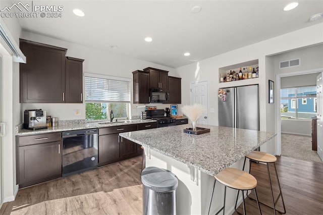 kitchen with a center island, sink, dark brown cabinetry, light colored carpet, and black appliances