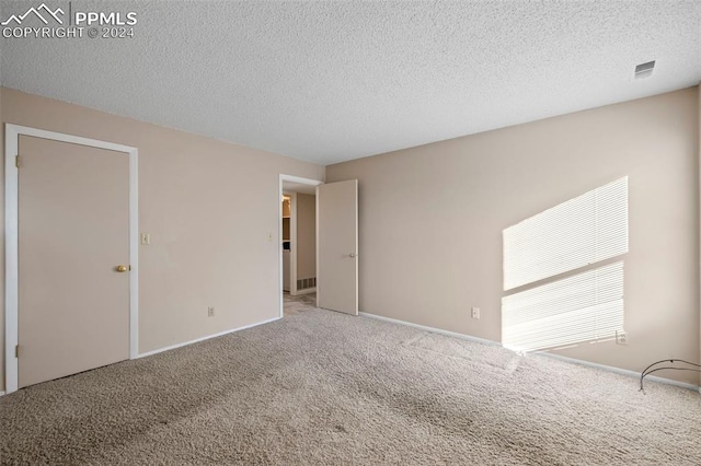 spare room with a textured ceiling and carpet floors