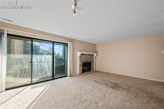 unfurnished living room with a fireplace, a textured ceiling, and carpet floors