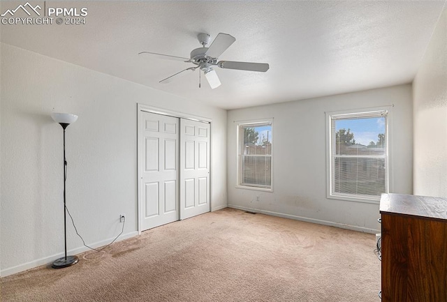 unfurnished bedroom with ceiling fan, light colored carpet, and a closet