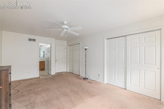 unfurnished bedroom featuring ceiling fan, connected bathroom, light carpet, and multiple closets