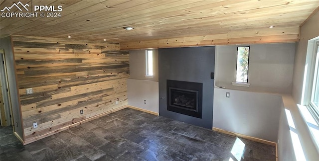 unfurnished living room featuring wood ceiling, wood walls, and plenty of natural light