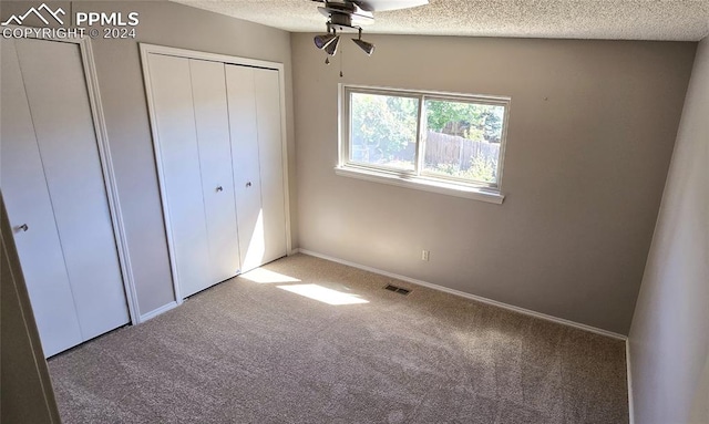 unfurnished bedroom with ceiling fan, a textured ceiling, lofted ceiling, and carpet flooring