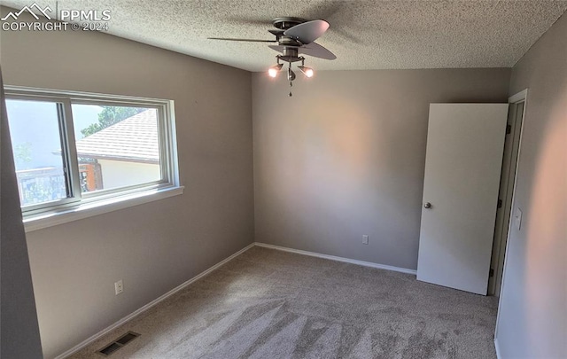 carpeted spare room with a textured ceiling and ceiling fan