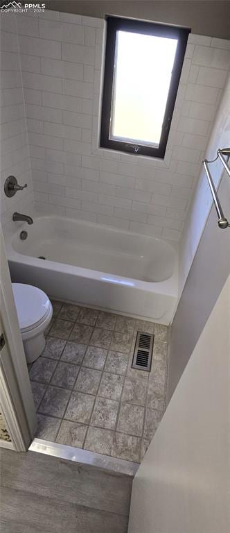 bathroom with tiled shower / bath combo and toilet