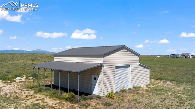 view of outbuilding featuring a mountain view, a yard, a carport, and a rural view