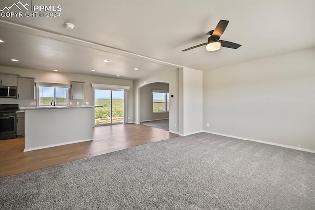 unfurnished living room with hardwood / wood-style floors, ceiling fan, and sink