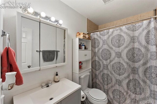 bathroom featuring vanity, toilet, and curtained shower