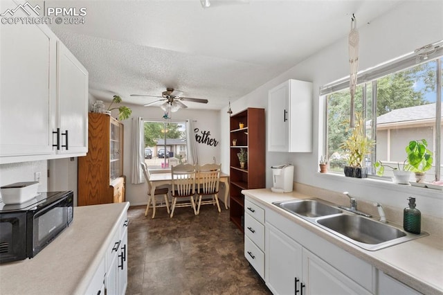 kitchen featuring white cabinets, dark tile patterned flooring, sink, ceiling fan, and a textured ceiling