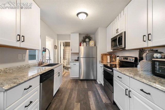 kitchen with dark wood-type flooring, sink, appliances with stainless steel finishes, and white cabinets