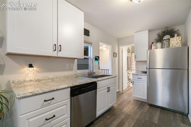 kitchen featuring appliances with stainless steel finishes, dark wood-type flooring, sink, light stone counters, and white cabinets