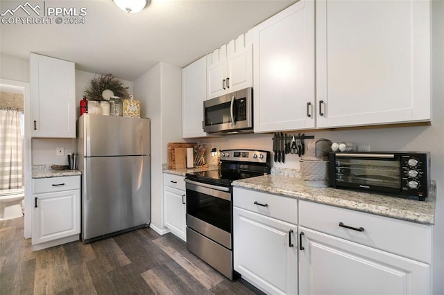 kitchen with light stone counters, appliances with stainless steel finishes, dark hardwood / wood-style flooring, and white cabinets