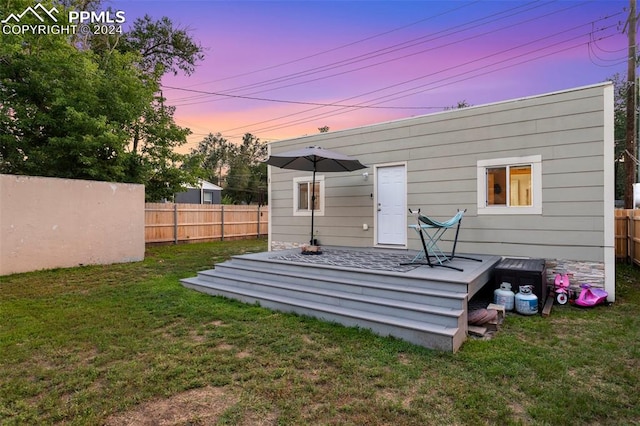 back house at dusk featuring a yard