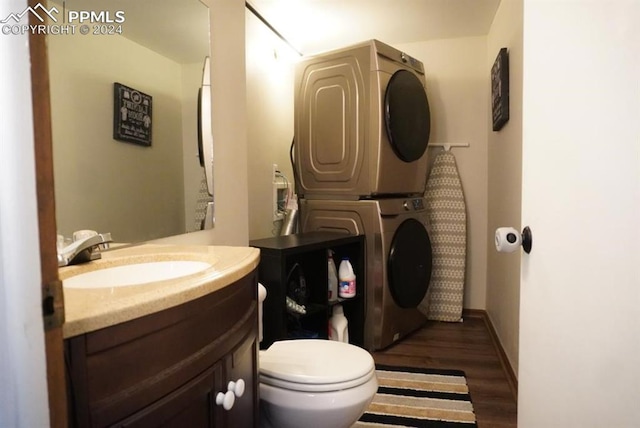 bathroom featuring vanity, toilet, wood-type flooring, and stacked washer and clothes dryer