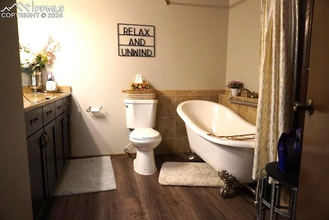 bathroom featuring a bathtub, hardwood / wood-style flooring, tile walls, toilet, and vanity