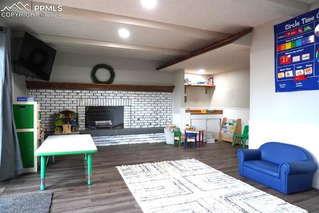 living room with beamed ceiling, a textured ceiling, a fireplace, and dark hardwood / wood-style flooring