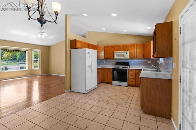 kitchen featuring light hardwood / wood-style flooring, vaulted ceiling, white appliances, a chandelier, and decorative backsplash