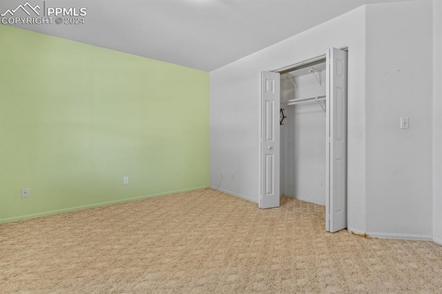 unfurnished bedroom featuring a closet and light carpet