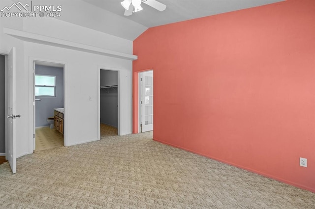 unfurnished bedroom with vaulted ceiling, ceiling fan, light colored carpet, and ensuite bathroom