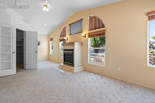 unfurnished living room with lofted ceiling and light colored carpet