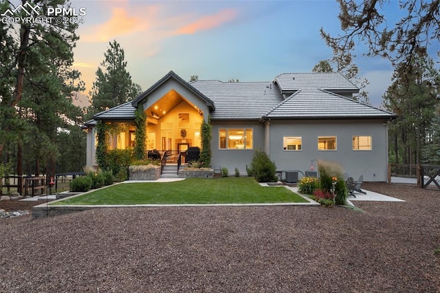 back of property featuring fence, a yard, stucco siding, a tiled roof, and a patio area