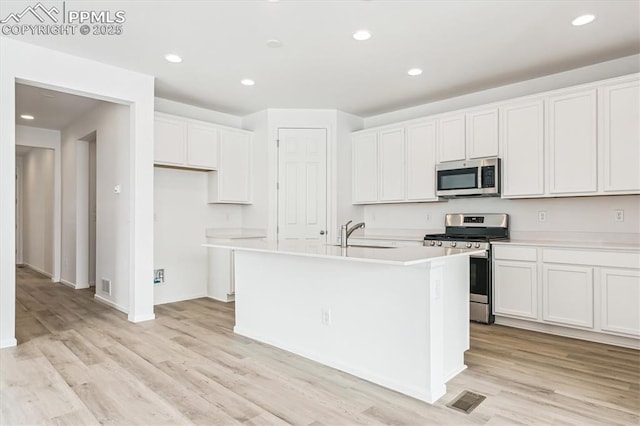 kitchen featuring visible vents, appliances with stainless steel finishes, white cabinets, and a sink