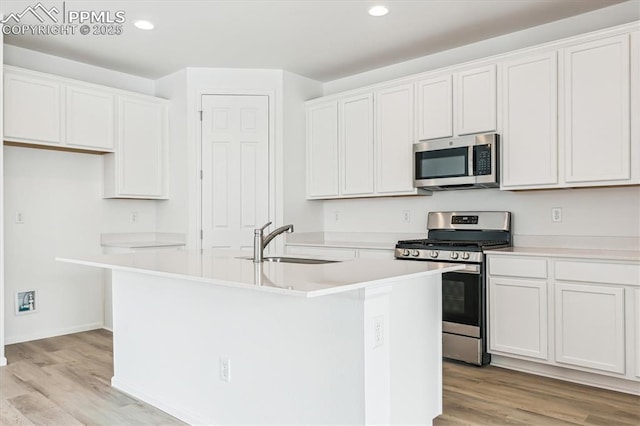 kitchen featuring a kitchen island with sink, recessed lighting, a sink, appliances with stainless steel finishes, and light wood finished floors