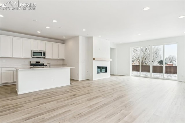 kitchen featuring appliances with stainless steel finishes, recessed lighting, open floor plan, and light wood-style floors