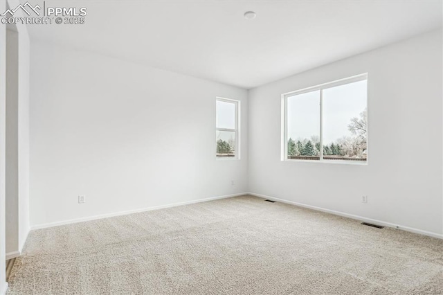 carpeted spare room featuring visible vents and baseboards