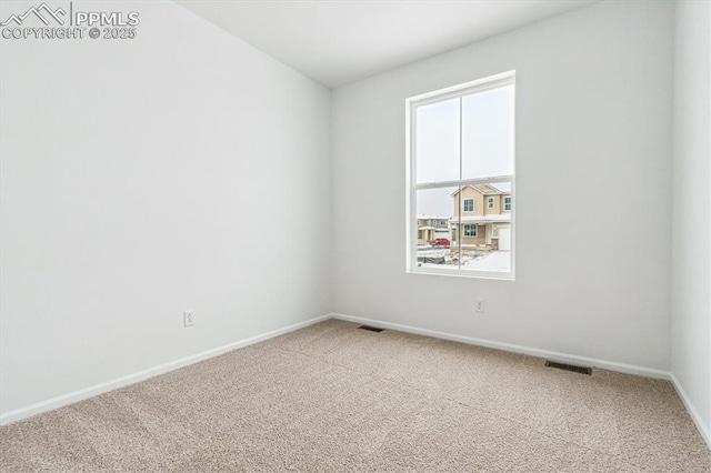 carpeted spare room featuring visible vents and baseboards