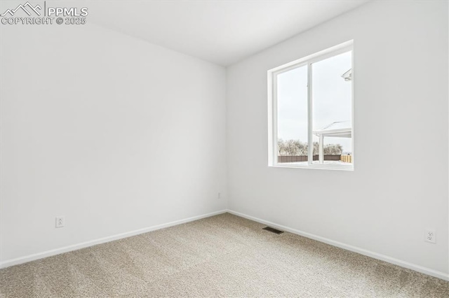 spare room with carpet floors, visible vents, and baseboards