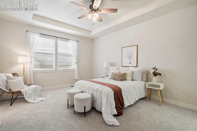 carpeted bedroom featuring ceiling fan and a tray ceiling