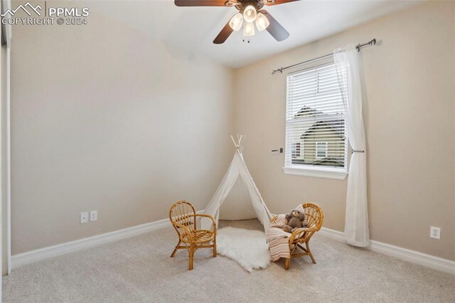 living area with light colored carpet and ceiling fan