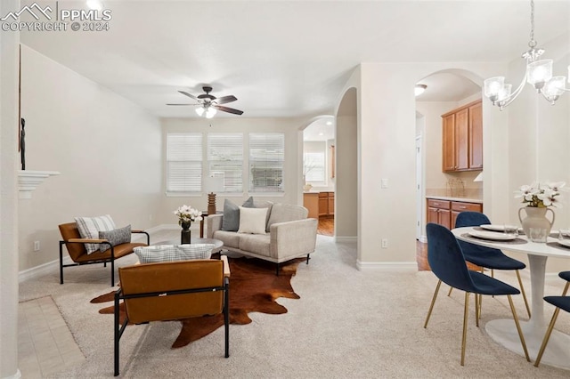 living room with ceiling fan with notable chandelier and light carpet