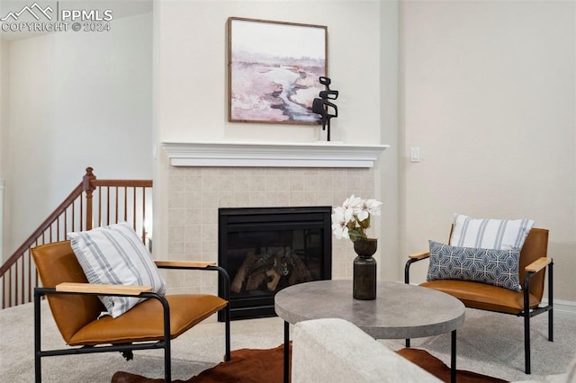 sitting room with a tile fireplace and carpet flooring