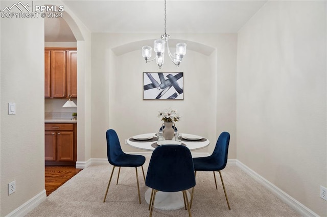 carpeted dining area with an inviting chandelier